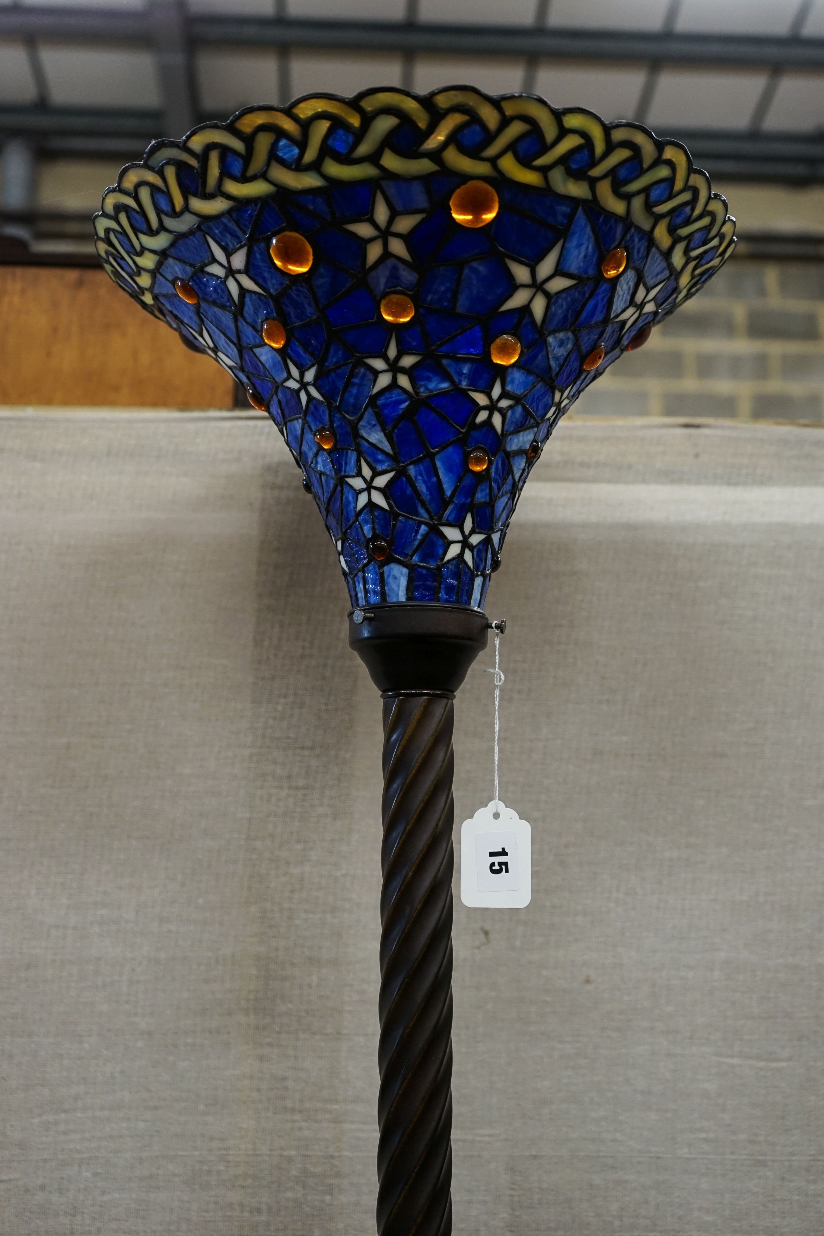 A bronzed finish Tiffany style uplighter floor lamp with flared blue leaded shade, 187cm high, 36cm diameter